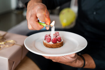 Closeup image of a man's hand lighting candles on a birthday cake