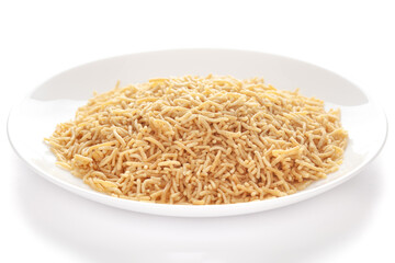 Salty plane Bhujia in a white ceramic  plate, made with Chickpeas or gram flour (Besan). Pile of Indian salty snacks (Namkeen), under backlight, side view