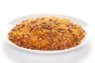 Diet Dal Bijli or Dal moth in a white ceramic plate, made with roasted Masoor Dal (black lentils). Pile of Indian spicy snacks (Namkeen), under backlight, side view