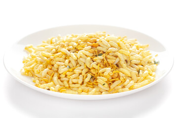 Crunchy Murmura in a white ceramic  plate made with Puffed Rice and Curry leaves. Pile of Indian spicy snacks (Namkeen)  under backlight side view against the white background.