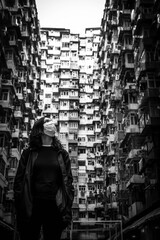 girl with mask looking up, with buildings behind, in black and white.	