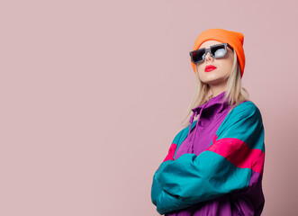 Style girl in 80s sportsuit and sunglasses on pink background