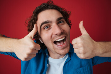 Excited handsome man in earphones showing thumbs up i