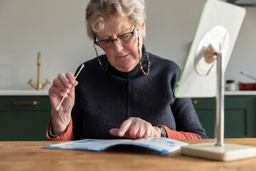 Naklejka na ściany i meble A woman reads through the instructions for a home coronavirus swab test