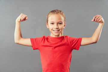 Cute joyful girl flexing her biceps and arm muscles