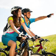ACTIVE Young couple biking on a forest road in mountain on a spring day - 410592494
