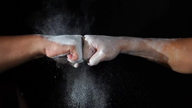 Two men fists attack with explosion powder on black background in slow motion. Sport concept for opening.