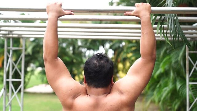 Slow motion of strong muscle man jump and hold the bar outdoor in sport.
