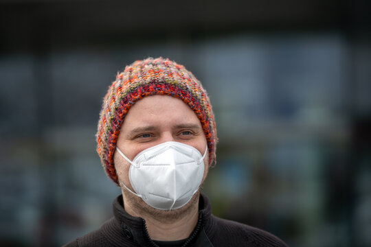 Mann mit lustiger bunter Wollmütze und FFP2 Maske gegen das Coronavirus