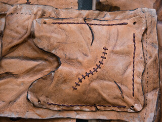 Leather pouch made of fresh zombie skin with scars stitched with dark brown thread top view