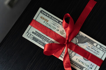 Money as a birthday present gift with red ribbon, dollar present