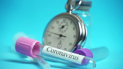 A chronometer, a stopwatch with medicines, a syringe and a bottle with the inscription coronavirus on a blue background. The concept of vaccination of the world's population. - Powered by Adobe