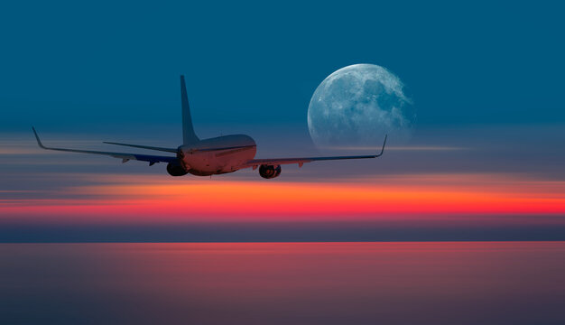 Passenger airplane flying away in to sky high altitude during sunset with full moon "Elements of this image furnished by NASA"