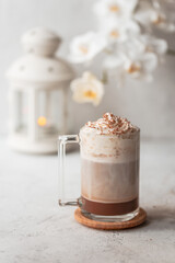 Hot latte macchiato with delicious foam in a tall transparent glass on an easy table setting. Photo...
