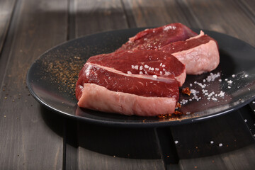 Raw beef steak for cooking on a plate on the kitchen desk.
