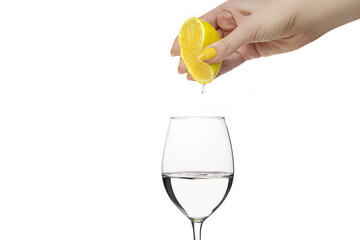 Female hand squeeze lemon in to the glass. Female hand with yellow manicure squeeze lemon. Lemonade...