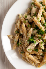 Homemade Chicken Alfredo Penne with Parsley on a white wooden surface, top view. Overhead, from above, flat lay. Close-up.
