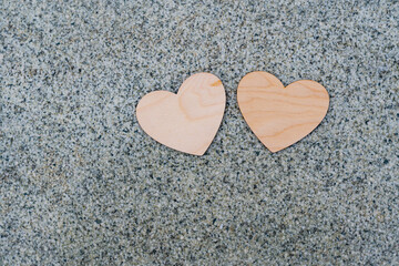Two light wooden hearts lie on a granite surface, a sign of love and fidelity, valentine's day 