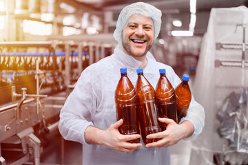 Brewery worker with bottles of beer in hands on packaging line background