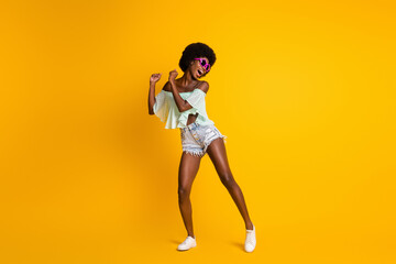 Fototapeta na wymiar Full length body size photo of black skinned girl wearing stylish summer clothes dancing on dance floor isolated on bright yellow color background