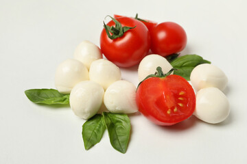 Mozzarella cheese, tomato and basil on white background, close up