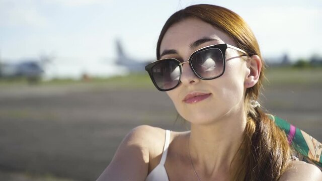 Beautiful Girl take off Sunglasses on the Background of the Plane
