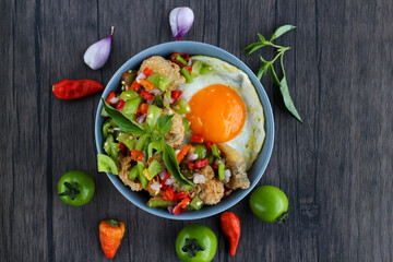Rice in a bowl filled with beef eye eggs and chopped fried fish smothered in very hot chili sauce.