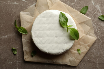 Baking paper with camembert cheese and basil on gray background
