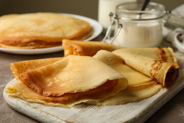 Concept of tasty breakfast with thin pancakes on gray table