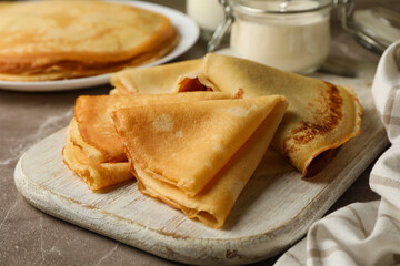 Concept of tasty breakfast with thin pancakes on gray table