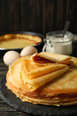 Concept of tasty breakfast with thin pancakes on wooden table