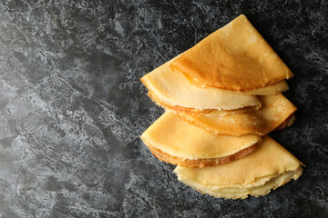 Delicious thin pancakes on black smokey background