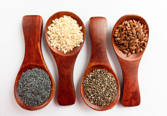 Wooden spoons with chia seeds, sesame seeds, poppy seeds, flax seeds on a white background. Healthy products concept.