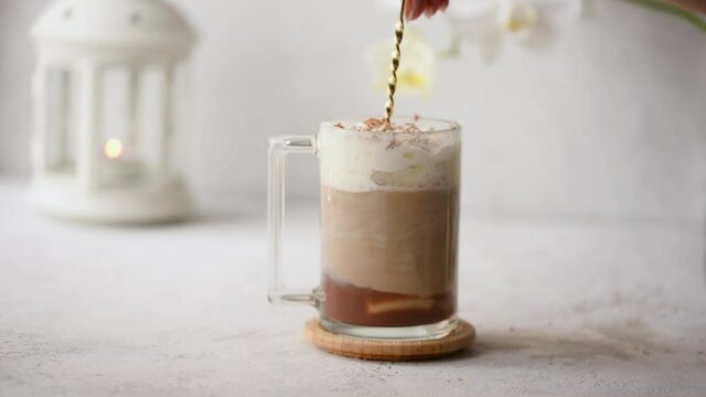 The process of placing a hot coffee mocha cocktail on a light rustic background. Breakfast at the cafe. Mixing of ingredients.