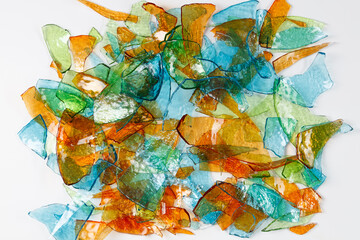 Background of broken fragments of colored multicolored glass with blurred reflections on white background .