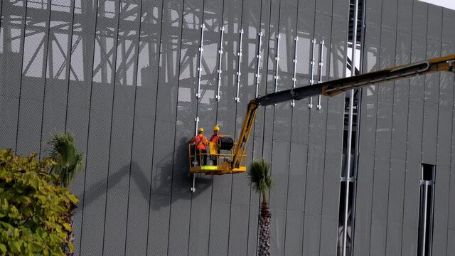 workers are installing a safety net with the help of the telescopic boom from the lifts platform