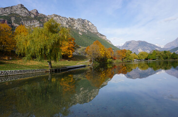 mirror reflection in the clear lake of the mountains and trees in the fall in the Southern Alps, France