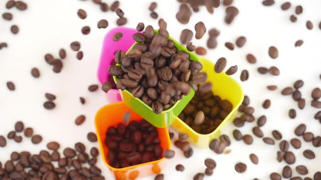 Close shot of dropping coffee seeds over plastic bowls filled with coffee beans