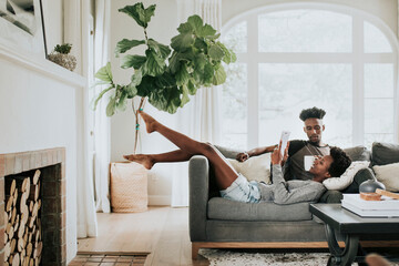 Cute romantic black couple reading a book on the couch - Powered by Adobe