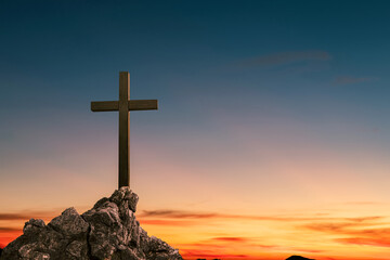 cross crucifixion on a mountain cliff rock With a sunset background