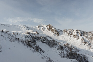 Alpine landscape, slopes of high mountains with glaciers against the blue sky.