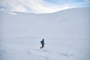 Fototapeta na wymiar Man mountaineer walking on the hill covered with fresh snow. Carpathian mountains