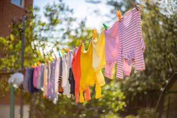 Baby cute clothes hanging on the clothesline outdoor. Child laundry hanging on line in garden on...