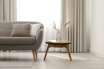 Grey sofa with pillows near window in stylish living room interior