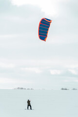 Back view Kite surfer ride on snowboard. Snowkiting in the snow on frozen field.
