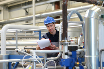 Techniker in einer Industrieanlage - Arbeiter kontrolliert Maschinen am Arbeitsplatz // Technician in an industrial plant - worker controls machines at the workplace
