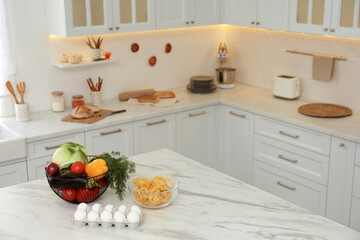 Modern kitchen interior with different products on white marble table