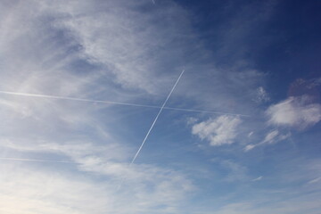Naklejka na ściany i meble Airplane flies leaving contrail trace on blue sky. Cross in the sky 