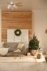 Spacious room with small Christmas tree and wreath. Interior design