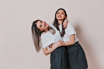 Asian girls in identical skirts and blouses posing on beige background